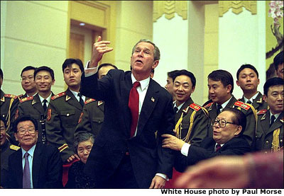 President George W. Bush motions for someone to join him and Chinese President Jiang Zemin for a group photo during a dinner in Beijing, China, Thursday, Feb. 21. White House photo by Paul Morse.